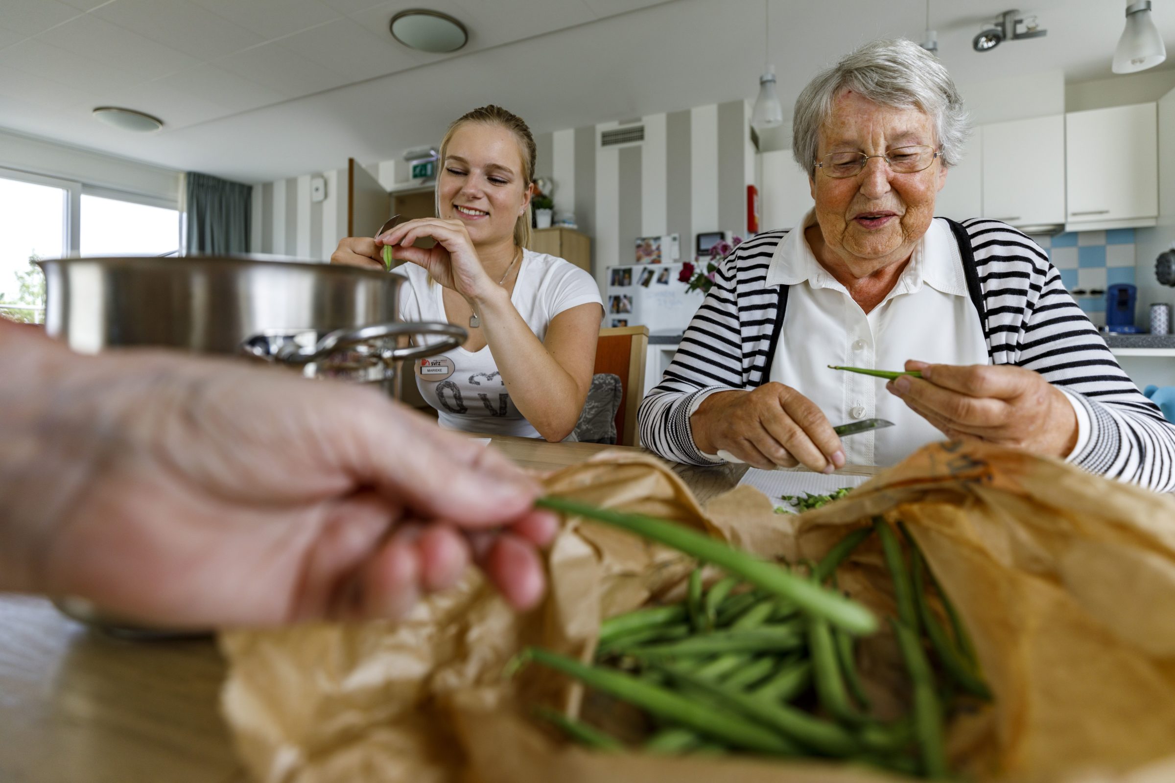 Medewerker en cliënt maken samen eten klaar in een woonruimte
