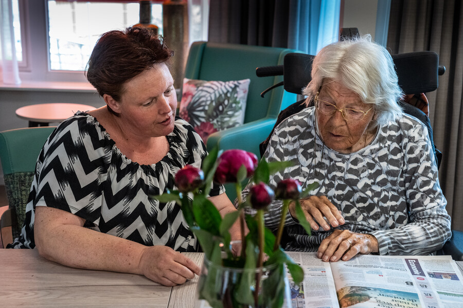 Medewerker en cliënt lezen samen de krant