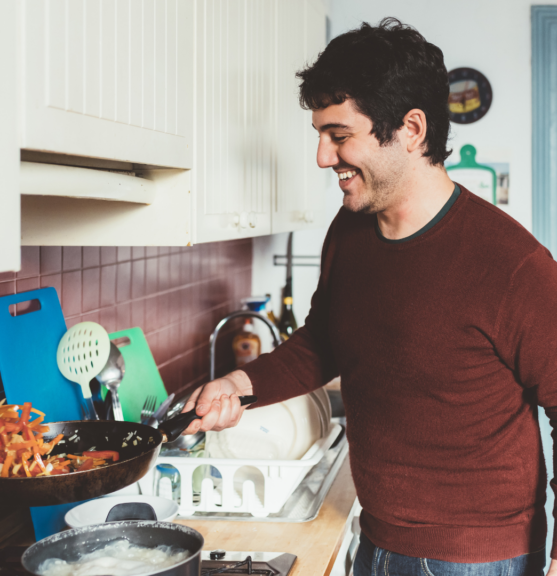 Vrijwilliger die samen met een oudere aan het koken is; koken met ouderen in een huiselijke keuken.