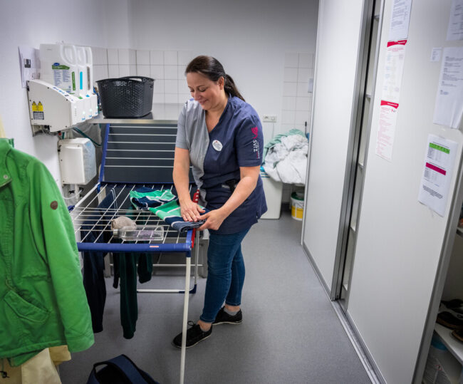 Medewerker hangt de was op een wasrekje