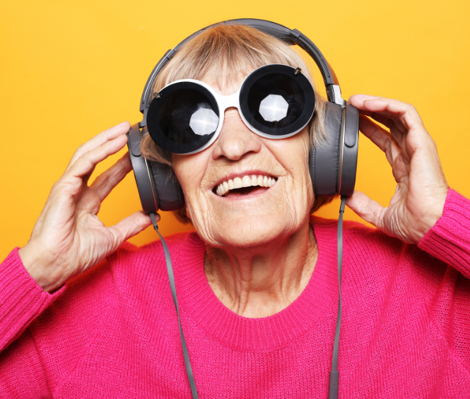 Een lachende oudere vrouw luistert naar muziek met een koptelefoon op
