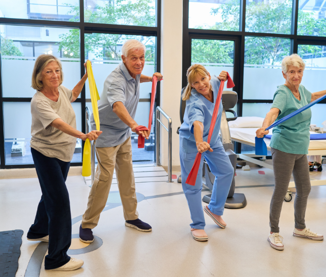 Een groep oudere mensen doet onder begeleiding een oefening met fitness elastieken