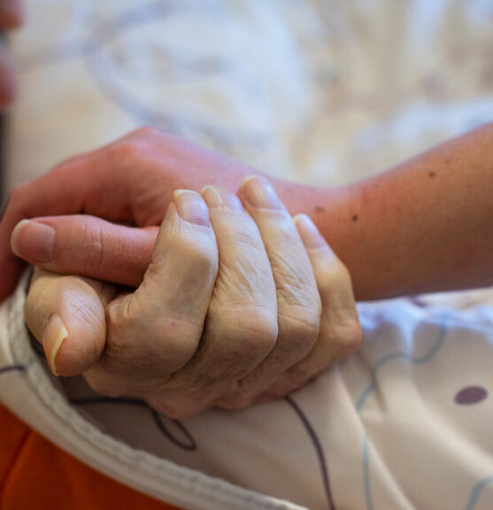 Een familielid die de hand vastpakt van een cliënt