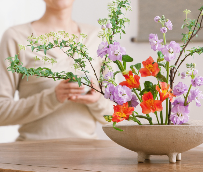 Vrouw kijkt naar bloemstuk op tafel