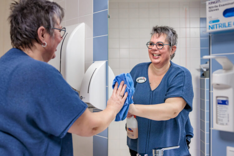 Medewerker maakt de badkamer schoon