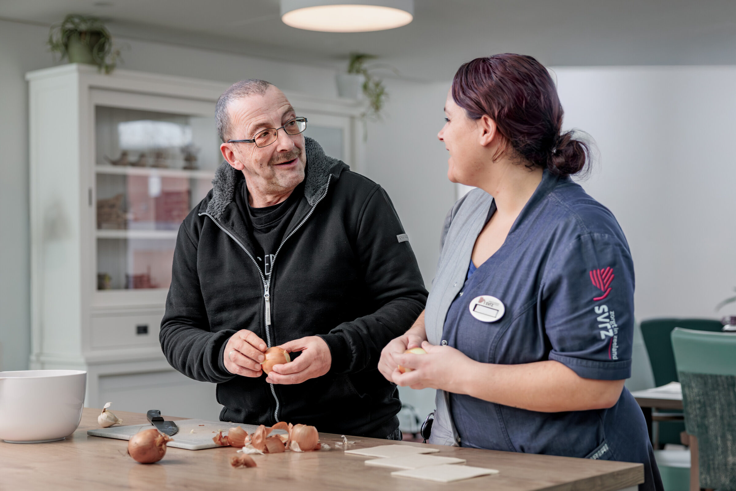Medewerker en cliënt maken samen eten klaar