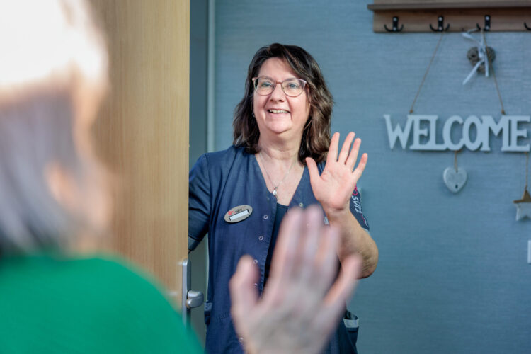 Medewerker heet bezoeker welkom aan de voordeur