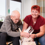 Dame en heer aaien een witte hond